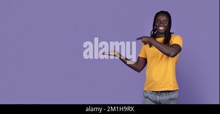 Positive african american guy holding something invisible on his hand Stock Photo