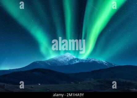 Aurora borealis over the snow covered mountain peak Stock Photo