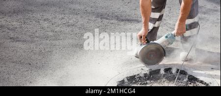 radial in the hands of asphalt worker cuts the soil Stock Photo