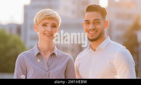 Portrait of diverse colleagues multiethnic co-workers caucasian business woman blonde short hair and hispanic bearded man stand posing looking at Stock Photo
