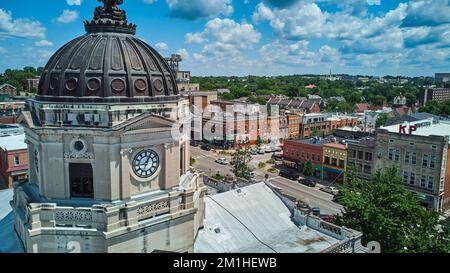 Up close to top of Bloomington Indiana courthouse clock with downtown in background Stock Photo