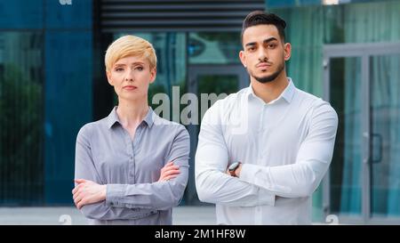 Multiracial couple of business colleagues serious co-workers caucasian mature woman with short hair and bearded hispanic man managers stand outdoors Stock Photo
