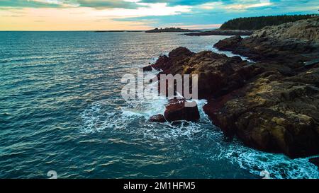 Serene ocean view over coasts of Maine with rocky coasts, waves crashing, and sunset light Stock Photo