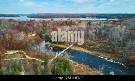 Suspension bridge over river in late fall from above Stock Photo