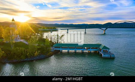 Tower and docks with bridge connecting New York to Vermont and sun setting behind mountains Stock Photo