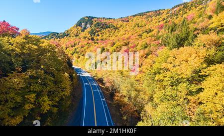 Aerial over road through New Hampshire mountains in peak fall Stock Photo
