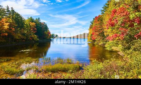 Low view of lake with blue skies and colorful fall hills Stock Photo