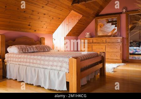 Timber frame double bed in master bedroom inside 1982 built replica of old 1800s log home, Quebec, Canada. This image is property released for calenda Stock Photo