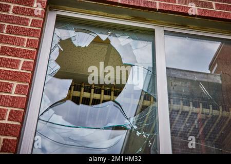 Broken glass window detail with multiple layers on brick building Stock Photo