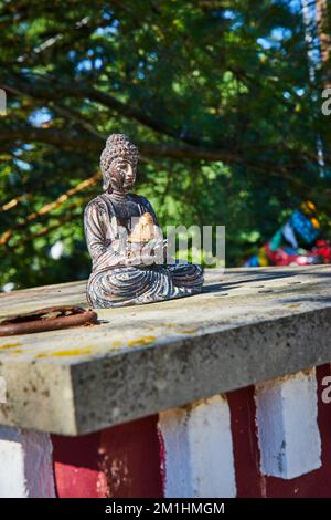 Cement square with small Buddhist statue resting on top Stock Photo