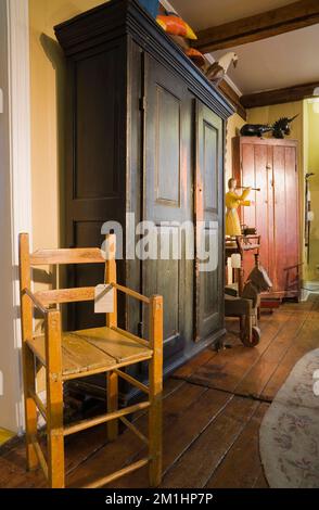 Antique wooden dark green and brownish red stained armoires and decorative objects and furnishings inside old 1810 home and antique store. Stock Photo