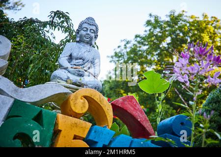 Colorful lettering and small stone Buddha statue at Tibetan Mongolian Buddhist shrine Stock Photo