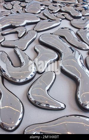 Abstract melted reflecting metal drops on floor Stock Photo