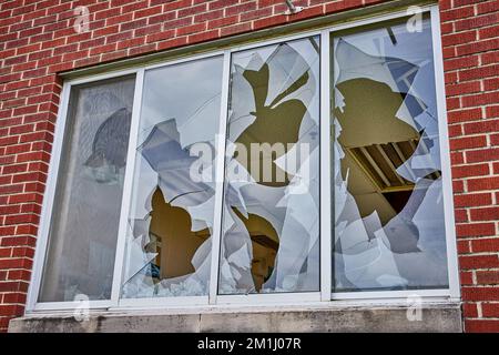 Detail of layers of broken glass on window outside with brick wall Stock Photo