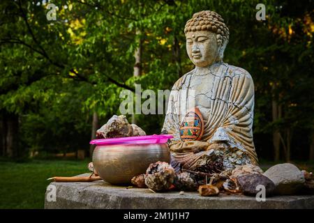 Buddhist prayer small statue with cracks and donations around Stock Photo