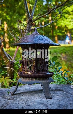 Small metal Tibetan Mongolian Buddhist lantern on rocks in forest Stock Photo
