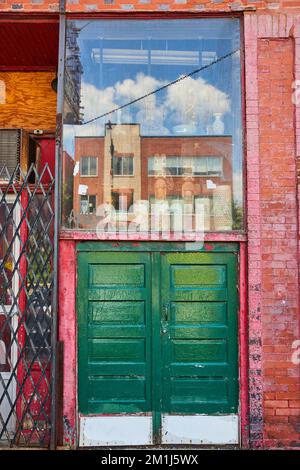 Alley large double green doors with glass display above along red brick wall Stock Photo