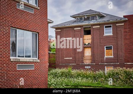 Abandoned brick buildings in fields with boarded up windows Stock Photo
