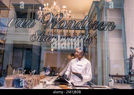 Amsterdam Netherlands December 2020, woman making a Stroopwafel in an Amsterdam shop a typical Dutch food two circular pieces of waffle filled with a caramel syrup Stock Photo