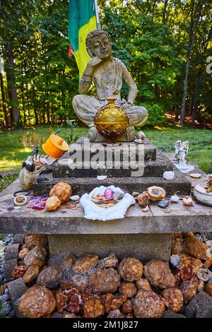 Geodes donated to small stone Tibetan Mongolian Buddhist statue in forest Stock Photo