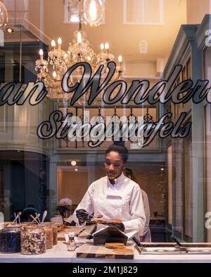 Amsterdam Netherlands December 2020, woman making a Stroopwafel in an Amsterdam shop a typical Dutch food two circular pieces of waffle filled with a caramel syrup Stock Photo