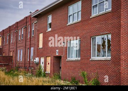 Detail of exterior brick wall on abandoned building with broken windows Stock Photo