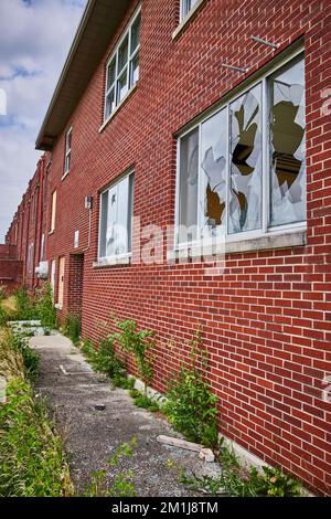 Broken windows on exterior of abandoned brick hospital in midwest America Stock Photo