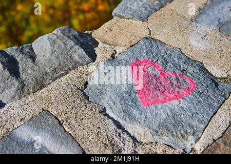 Stone wall detail of pink heart graffiti Stock Photo