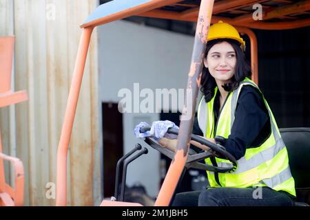Young asian woman is foreman driving forklift at distribution warehouse, engineer working and shipping container at factory, cargo and logistic, one p Stock Photo