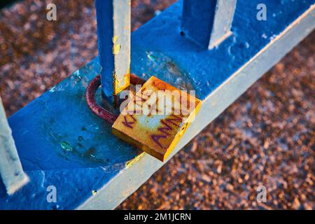 Rusty lock on blue railing with Kane + Anna carved on Stock Photo
