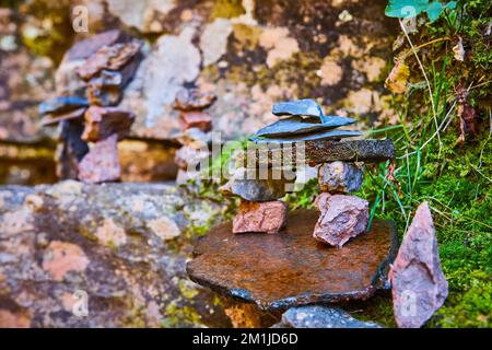 Beautiful small stone stack cairn forming bench against lichen rocks and moss Stock Photo