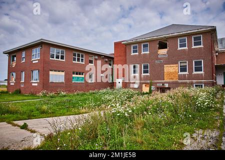 Three story abandoned brick buildings with overgrown fields Stock Photo ...