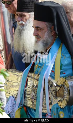 A Greek Orthodox priest carrying a silver icon of the Virgin Mary ...