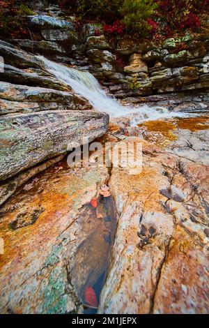 View of rocks in riverbed with puddle of water and waterfall in background Stock Photo