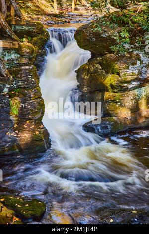 Detail of small waterfall through rocks covered in lichen and moss Stock Photo