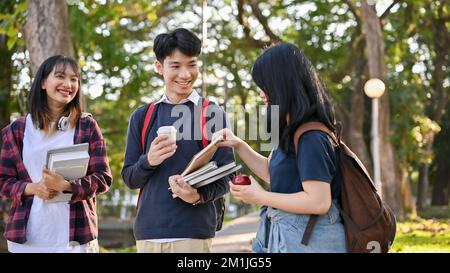 Happy Asian high school students enjoy talking and laughing together while walking in the school's park. Stock Photo