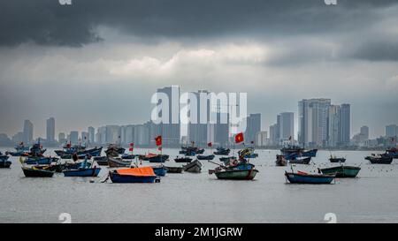 Traditional Vietnamese wooden fishing boats moored off My Khe beach across the bay from the modern sea front at Danang, Vietnam. Stock Photo