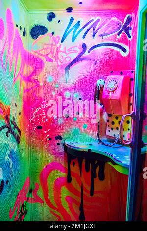 Phone booth fully painted in vibrant glowing colors Stock Photo