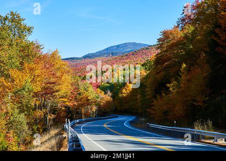 Looking down road from side in mountains during peak fall with colorful foliage Stock Photo