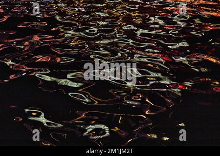 Detail of river at night with blue and red lights reflecting on highlights Stock Photo