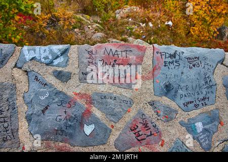Looking down on stone block wall covered in graffiti with drop off to forest Stock Photo