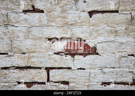 Detail of red brick wall painted white and decaying with cracks Stock Photo