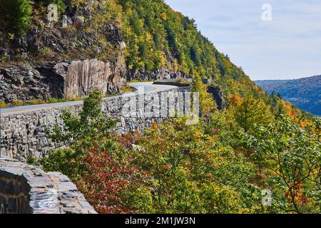 Beautiful highway winding through cliffs and mountains with stone wall supporting edge Stock Photo