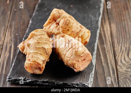 Fresh ginger on black stone on wooden background Stock Photo