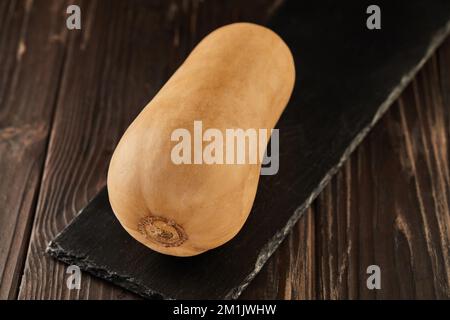 Pumpkin pear-shaped on black stone on wooden background Stock Photo