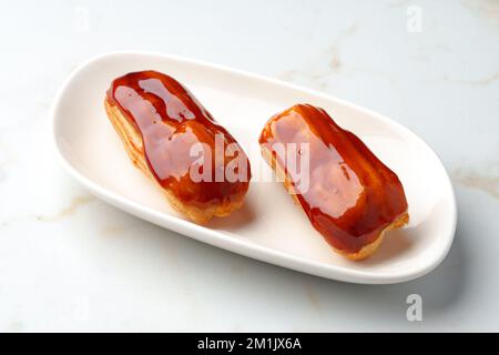 Two caramel eclairs on a white plate Stock Photo