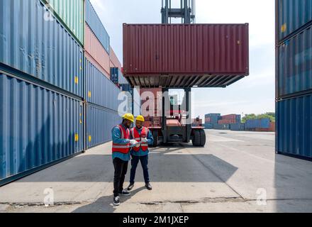 Two short black hair man with moustache and beard dressed in hardhat, safety vest and protective glove working during the day under sunlight. There ar Stock Photo