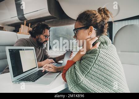 Couple of traveler worker using laptop together inside a camper van modern digital nomad house. Living and working off grid for freedom and economy. M Stock Photo