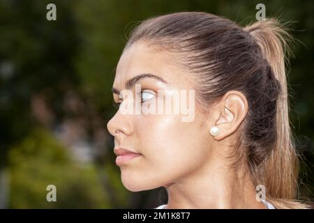 Portrait of a smiling woman sitting on the ground in the city street after running. A healthy runner resting after exercise. Active sporty woman Stock Photo