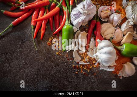 Fresh chilli, peppers and garlic along with dried chilli on a kitchen bench Stock Photo
